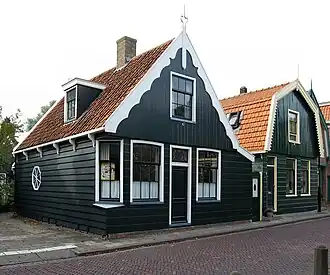 Houten huis voorzien van voorschot met geschulpte lijst en topmakelaar met Lod.XVI-ornament