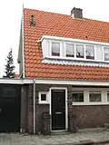 Blok met 8 keukenwoningen, zo genoemd vanwege destijds nieuwe plaatsing van keuken aan de voorzijde, aan de zijkant een houten topgevel, bouwstijl Amsterdamse School, samen met de poortgebouw langs de Purmerweg centraal deel van Tuindorp Nieuwendam