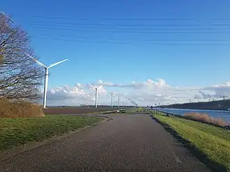Tien van de 13 windmolens bezuiden de A58. Aan de horizon kerncentrale Doel.