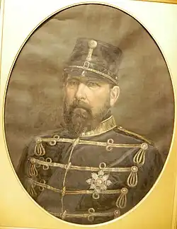 Foto in een ovaal passe-partout. Geportretteerde is een man met een militair uniform en een donkere baard.