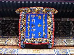 Bord boven de ingang van de tempel. De naam van de tempel staat vermeld (van rechts naar links) in het Mantsjoe, Hanzi, Tibetaans en Mongools