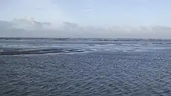 Golven breken over de zandbank en voegen water toe