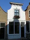 Huis met klokgevel met bepleistering en lijst