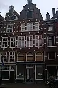 Pand met gevel met geblokte muurdammen, nog in het bezit van de oude top, bekroond door segmentvormig fronton met schildhoudende leeuw