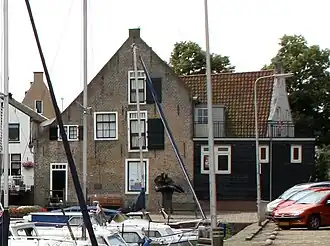 Nettenpakhuis. Pand onder met pannen gedekt zadeldak, evenwijdig aan de straat, tussen puntgevels met vlechtingen. Vooruitspringende vleugel, die met het pakhuis een L-vormige plattegrond uitmaakt en dienend als woonhuis. Dit gedeelte heeft een gepleisterde gevel met inzwenkende zijkanten